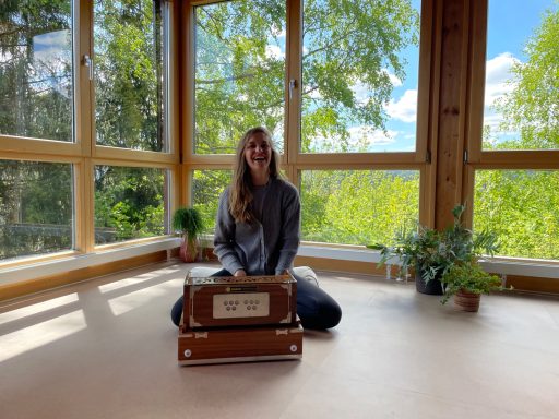 Julia hinter dem Harmonium im großen Yogasaal mit Blick in den Schwarzwald 