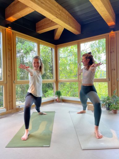 Julia und Fee im Krieger I nebeneinander auf der Yogamatte